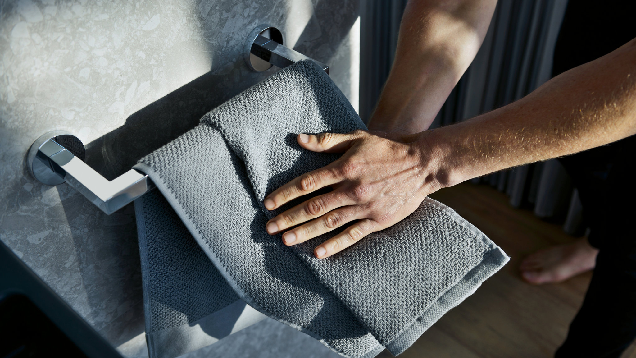 Männerhände an Handtuch im Handtuchring der Edition 90