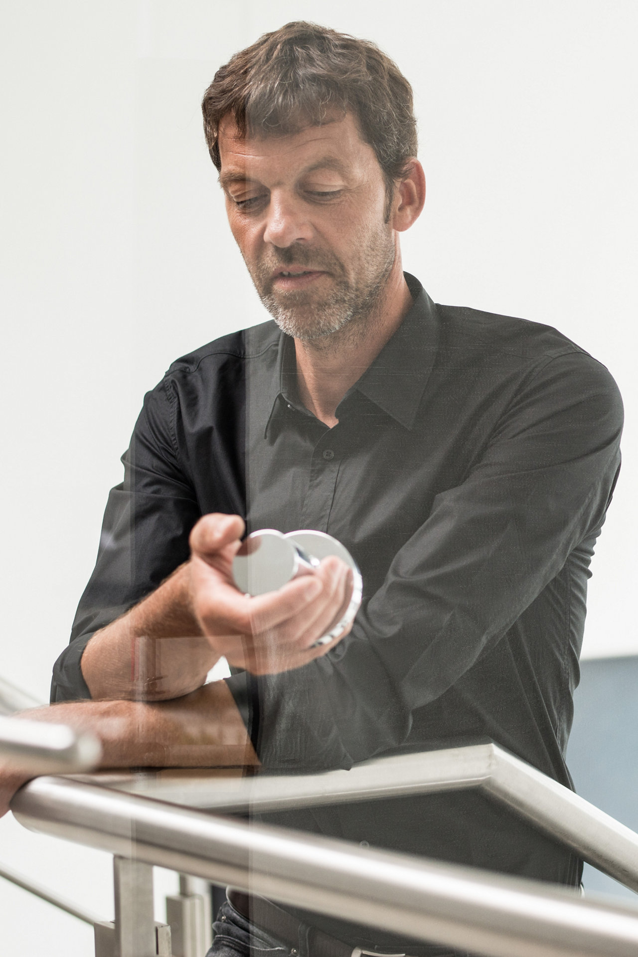 Dominik Tesseraux steht an einem Geländer und hält ein IXMO Element in der Hand
