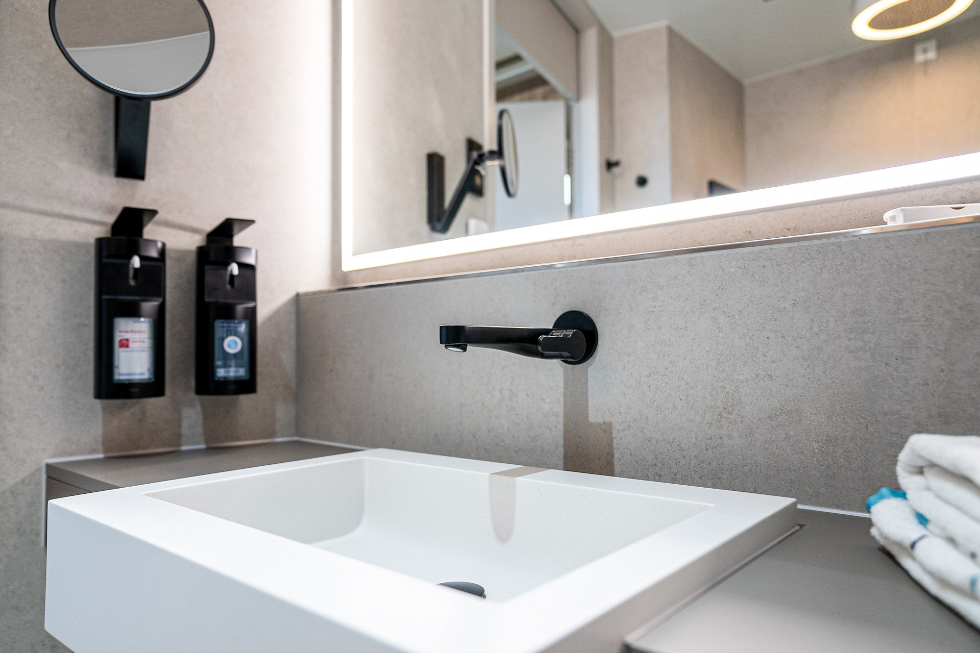 Klinikum Garmisch-Partenkirchen Badezimmer Waschtisch mit IXMO Armatur, iLook_move Kosmetikspiegel und PLAN Hygienemittelspender in Schwarz matt