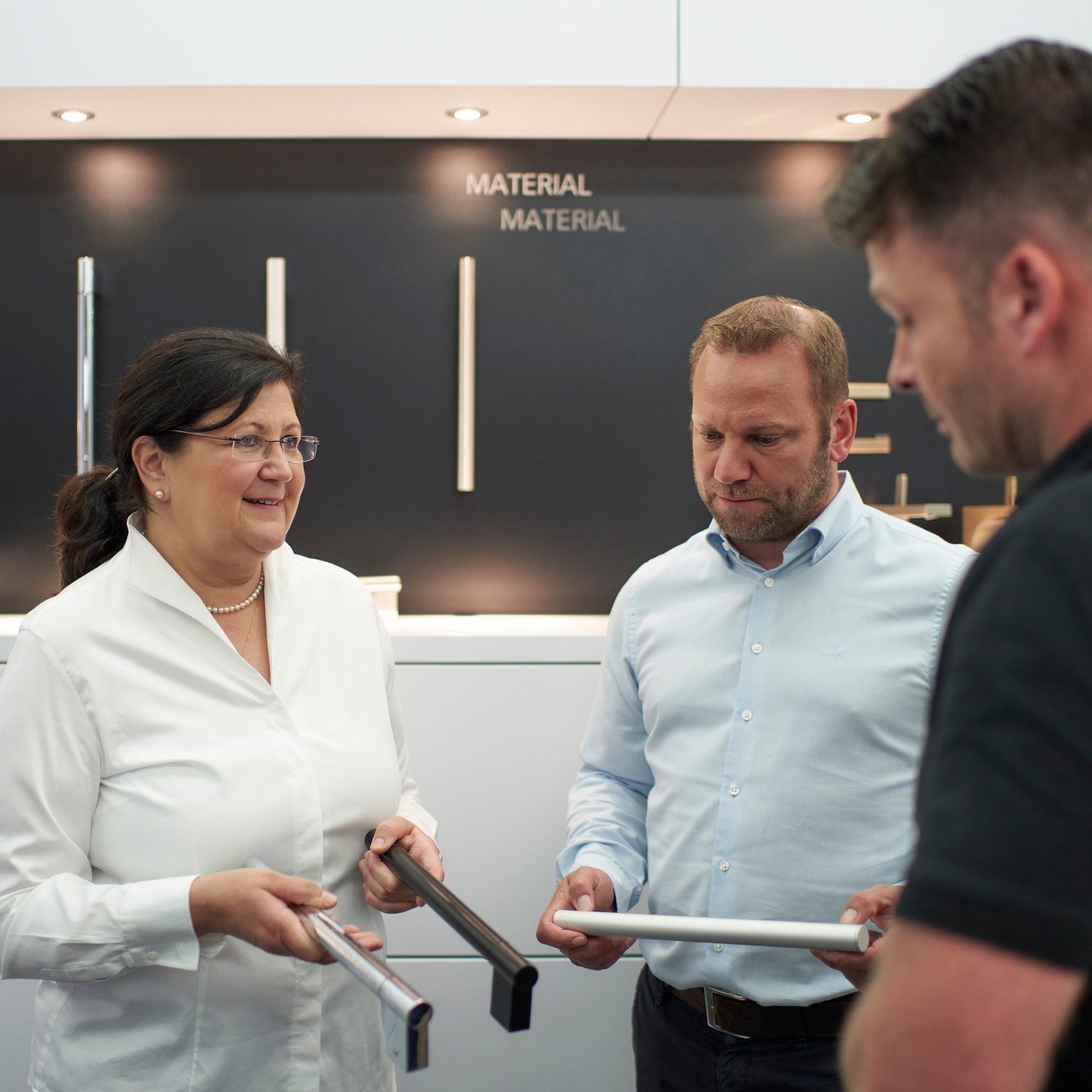 Trainingsleiterin präsentiert zwei Männern verschiedene Handtuchhalter