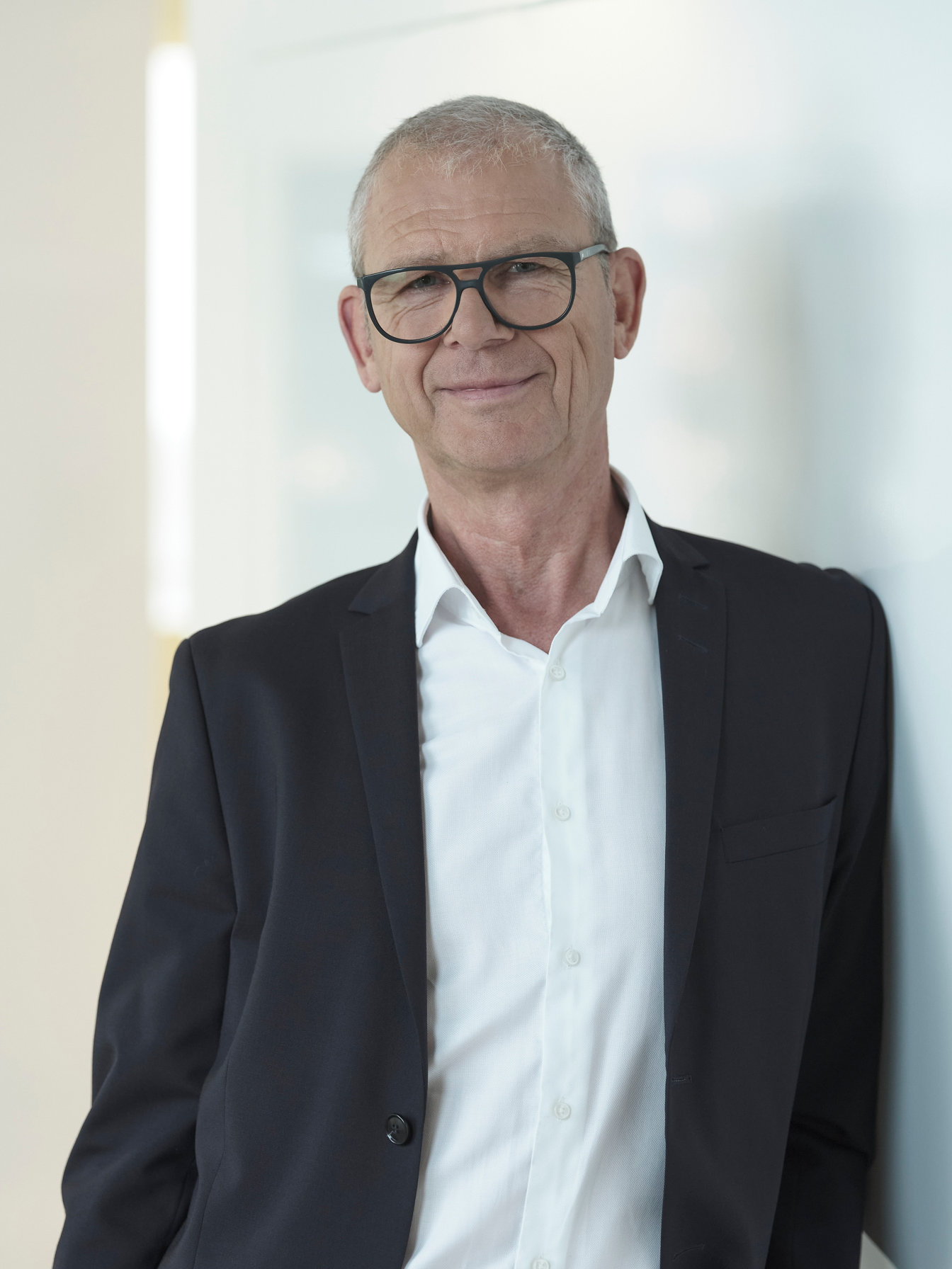 Portrait Andreas Lohmann nah an Wand gelehnt