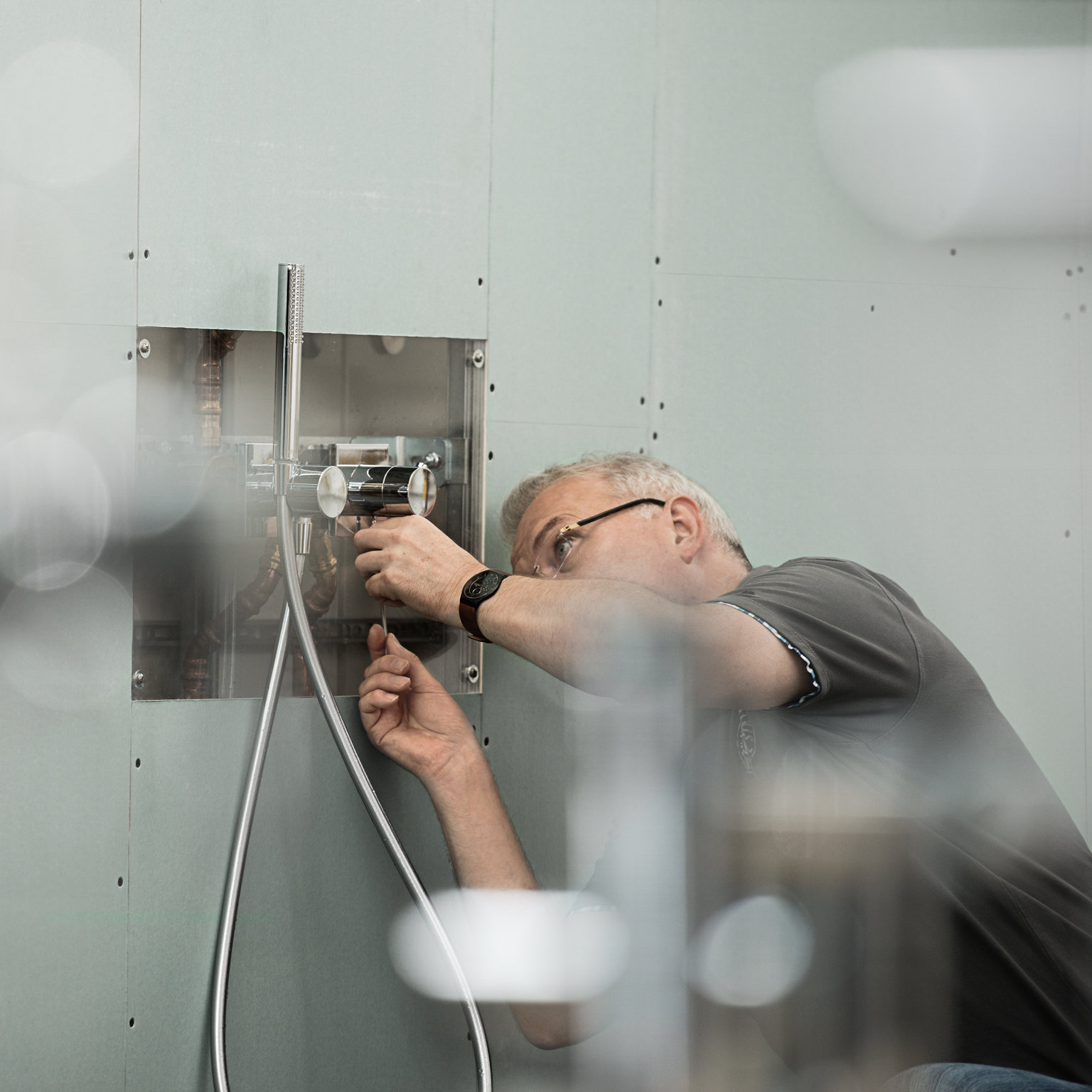 Mann mit Brille montiert eine IXMO Duscharmatur