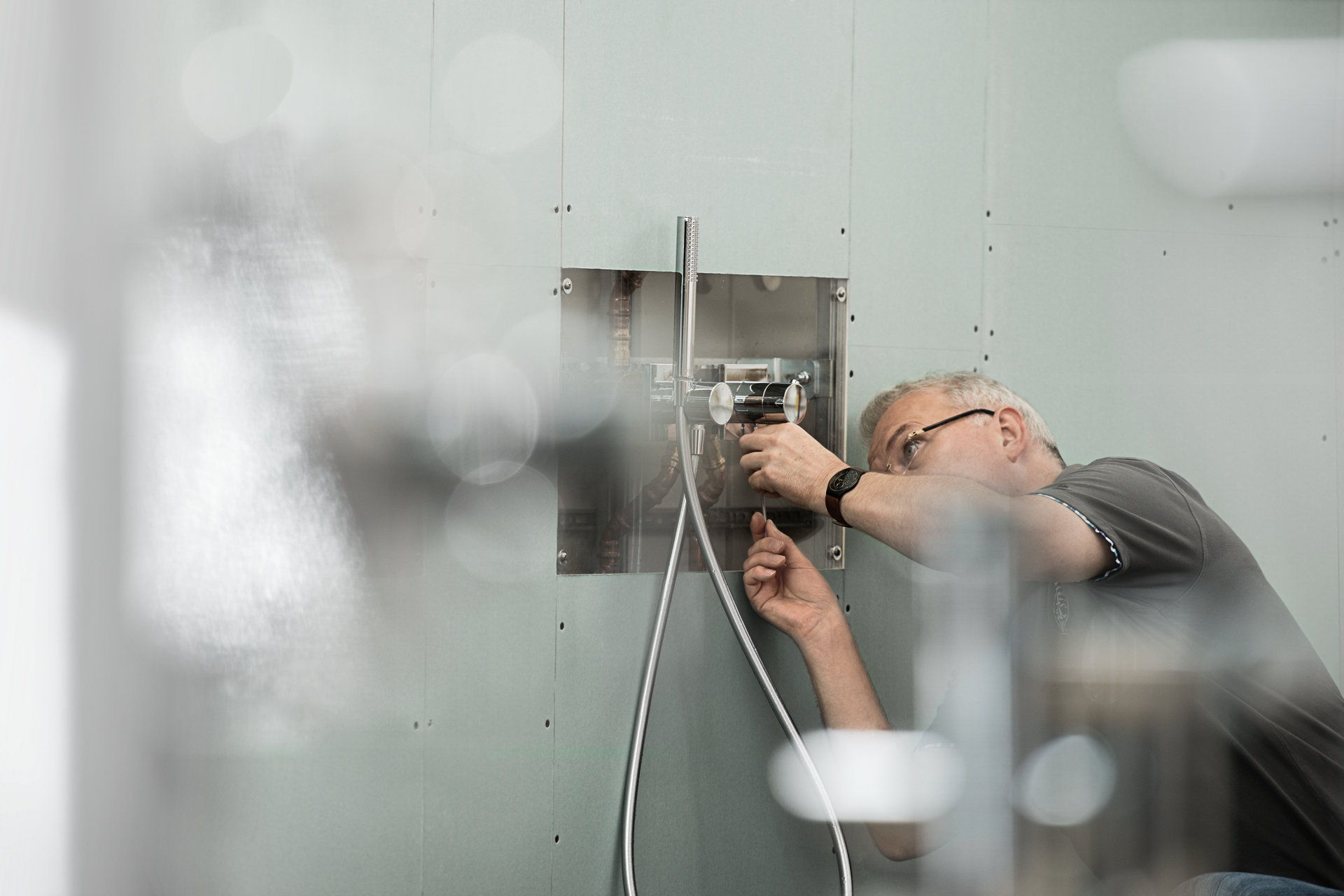 Mann mit Brille montiert eine IXMO Duscharmatur