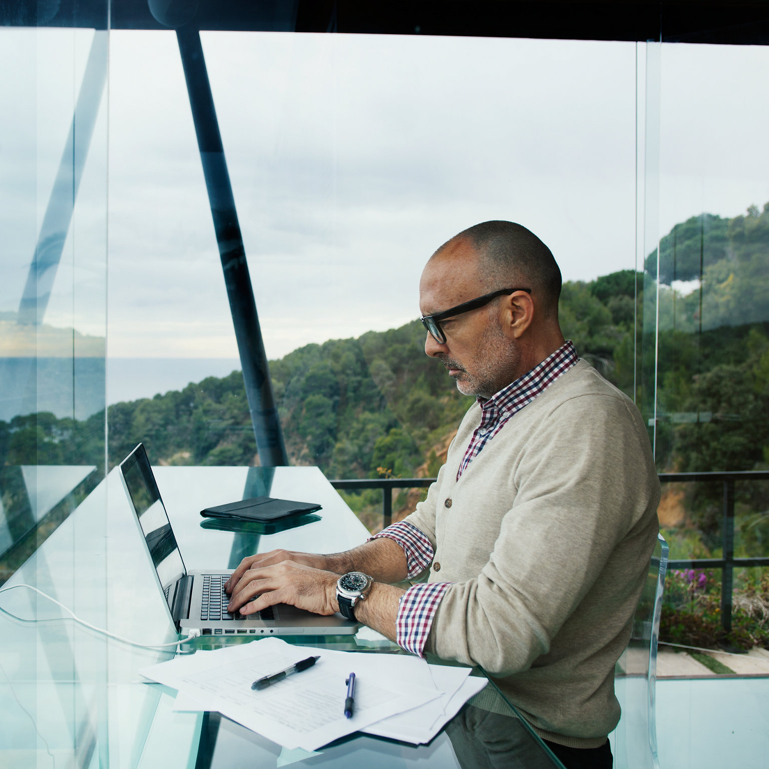 Arbeitender Mann am Laptop am verglasten Arbeitsplatz