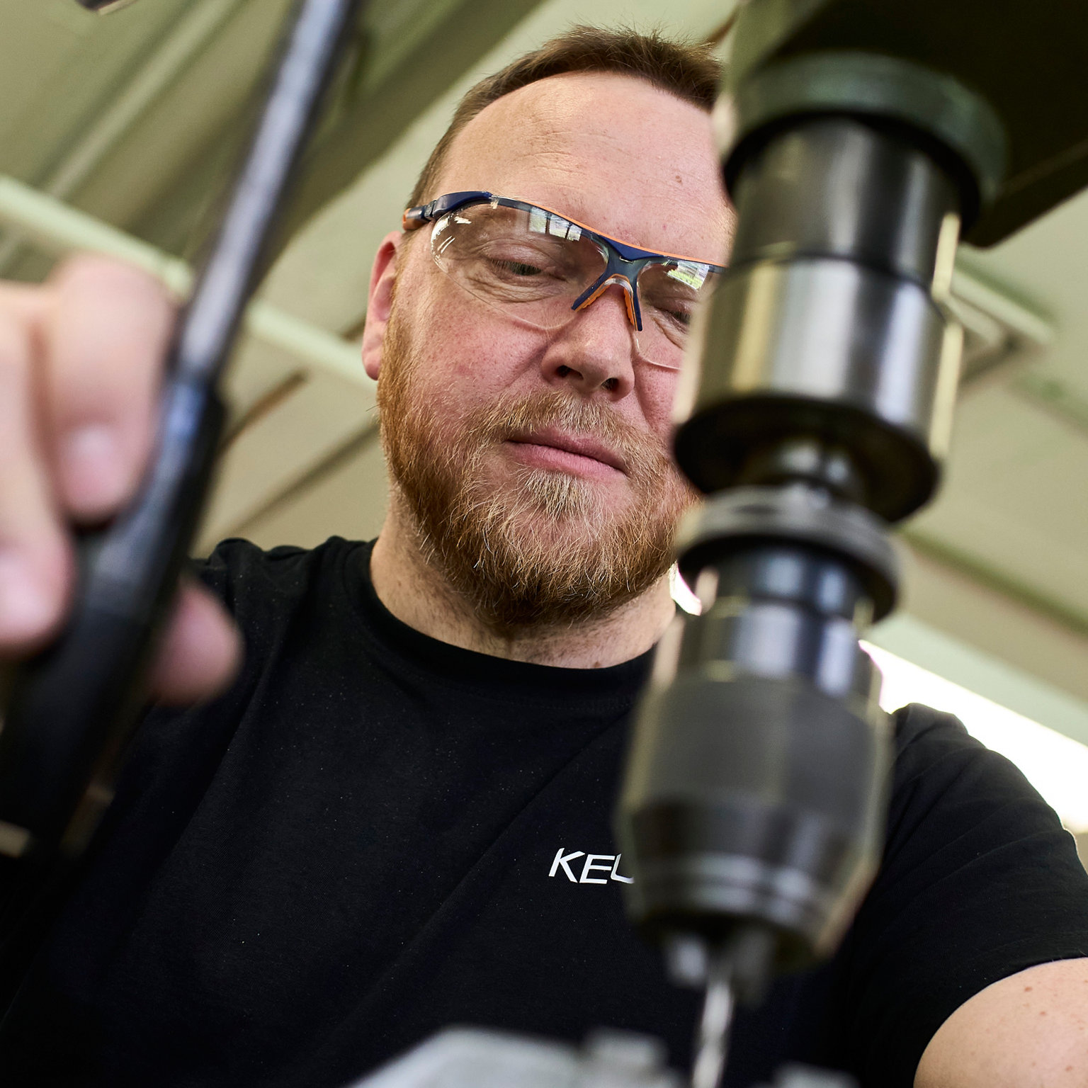 Konzentrierter Mitarbeiter in KEUCO Tshirt bedient einen Bohrer