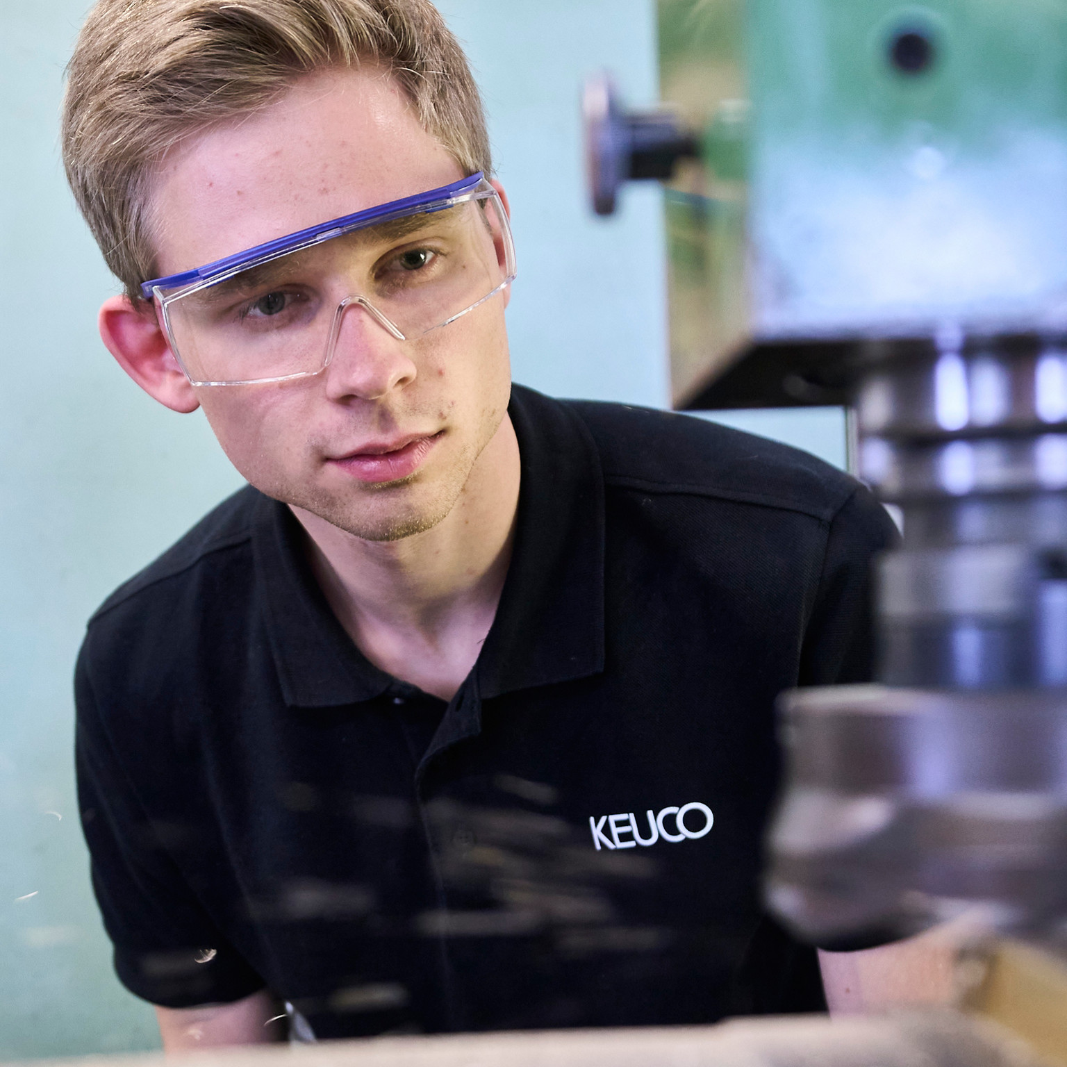 Mitarbeiter mit KEUCO Tshirt und Schutzbrille beobachtet aufmerksam den Vorgang in einer Maschine