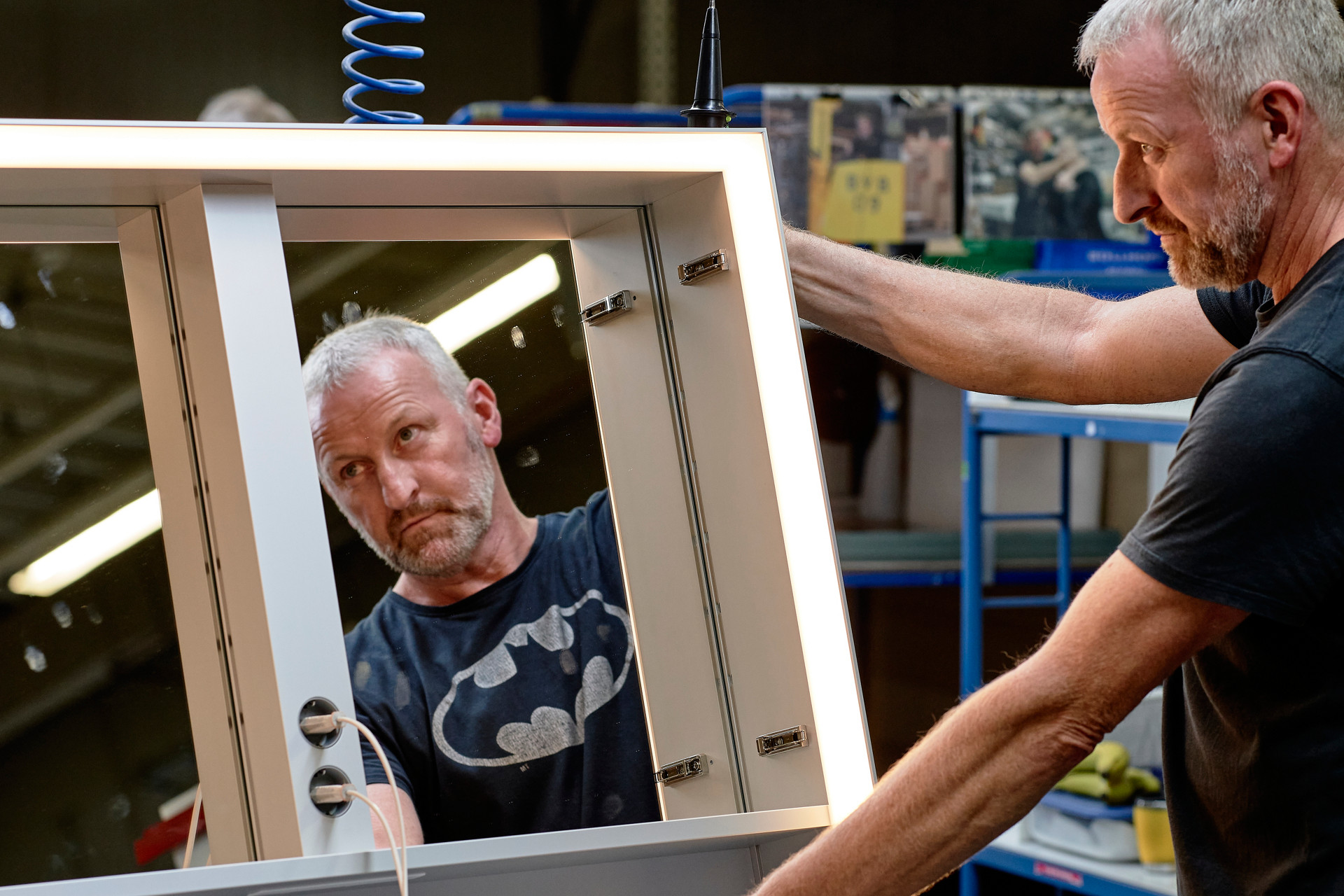 Fabrikmitarbeiter spiegelt sich in Spiegelschrank während er das Produkt aufrichtet