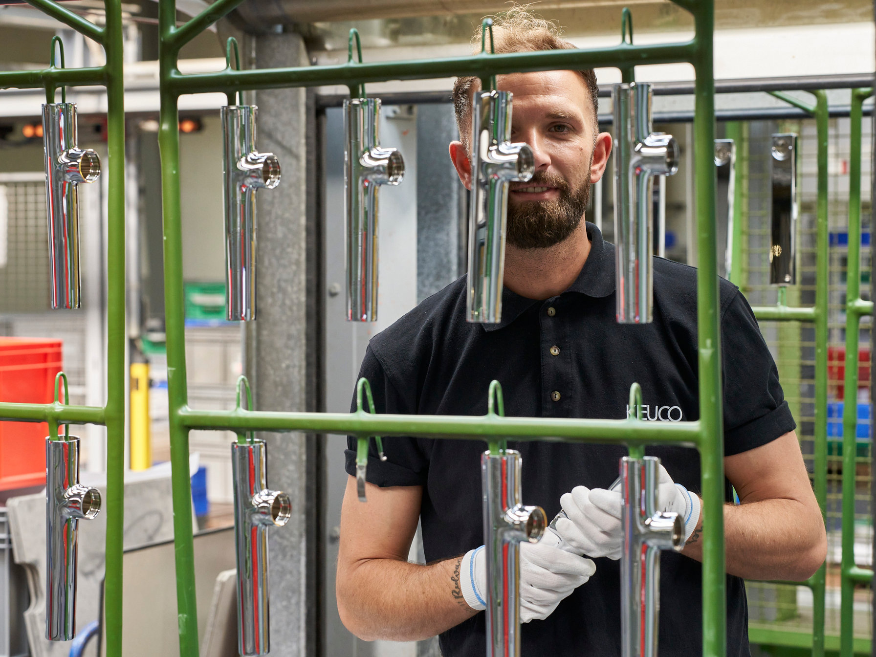 Mitarbeiter hinter hängenden Armaturen hält ein Produkt in den Händen  lächelt in die Kamera