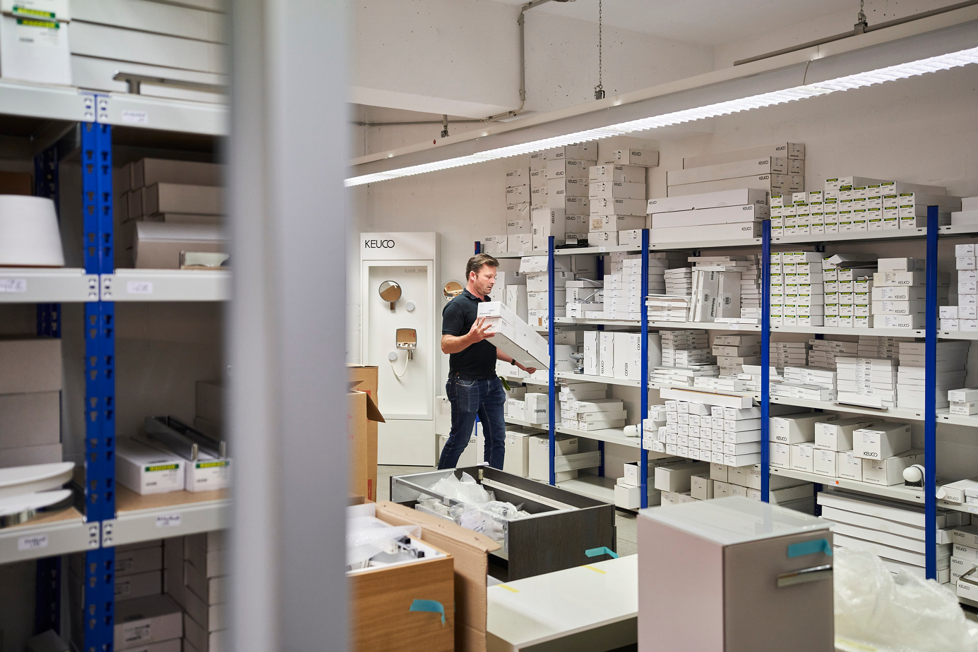 Mitarbeiter trägt zwei Kartons durch den Werksverkauf